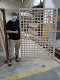 Youth standing beside wood trellis in the YOU Woodshop.